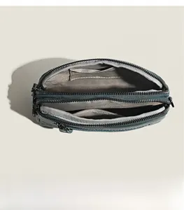 Detailed interior of dark green pebbled leather crossbody bag with dual zipper layers