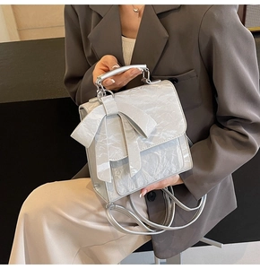 Detail of silver marble texture bag with large bow and metallic handle on model