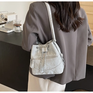 Detail of silver pleated bucket bag with metallic chain and stylish zip pocket