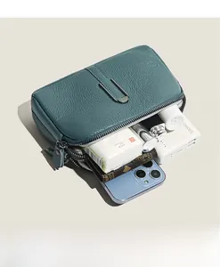 Detailed interior of a teal pebble leather crossbody bag showing multiple organized pockets