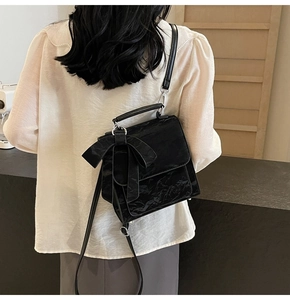 Rear view of a black crossbody bag with bow detail and crinkled texture on a model