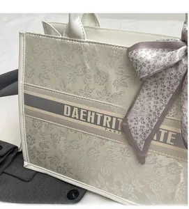 Detailed view of floral embroidery on cream canvas tote bag with silk scarf charm