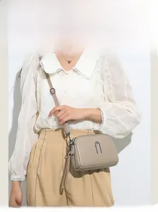Detail view of khaki crossbody bag with litchi texture, multi-zipper layers, and strap