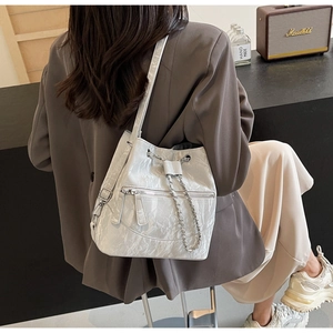Detailed view of silver glossy bucket bag with drawstring closure and chain strap