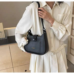Détail du sac seau en cuir noir avec fermeture éclair dorée et breloque mouton