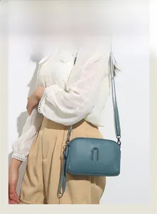Detail shot of a teal textured leather shoulder bag with metallic U-shaped closure