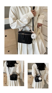 Detail of black quilted box bag with decorative scarf handle and white plush charm