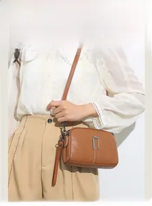 Caramel brown pebbled leather crossbody bag with silver U-shaped metal buckle on model