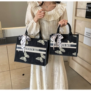 Close-up of black butterfly embroidered tote bags in two sizes with silk scarf details