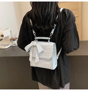 Detailed view of light blue textured leather backpack with a bow on a female model
