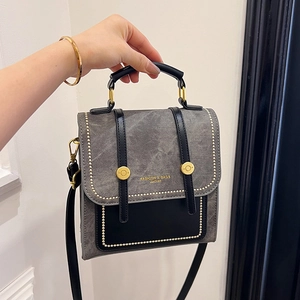 Grey textured tote bag with black leather handles and gold rivet accents for women