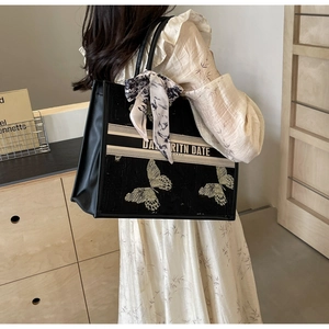 Close-up of black canvas tote bag with sequined butterfly embroidery and striped ribbon