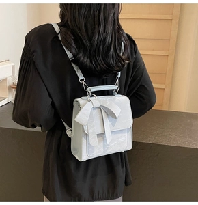 Detailed view of the mini light blue backpack with a large bow decoration on model