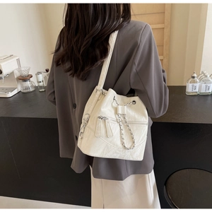 Detailed back view of white bucket bag featuring drawstring closure and silver chain strap