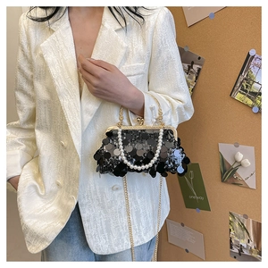 Details einer schwarzen Pailletten-Abendtasche mit Perlengriff und goldenem Verschluss