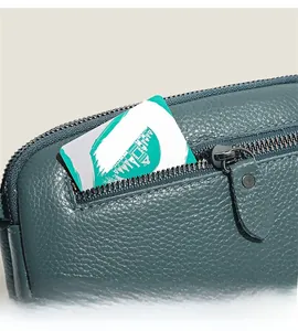 Detailed close-up of teal lychee grain leather crossbody bag with smooth zipper pocket