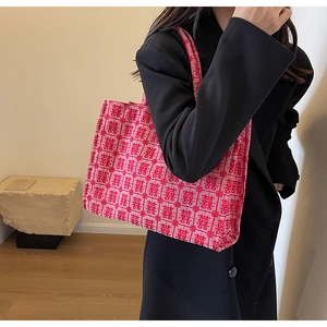 Detail of red canvas tote bag featuring traditional jacquard patterns and sturdy handles