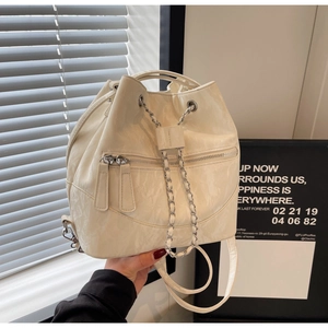 Detail of cream white bucket bag featuring silver chain and wrinkled leather texture
