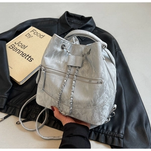 Detail of silver metallic drawstring bucket bag with pleated texture and chain straps