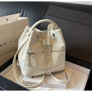 Detailed view of white bucket bag with marble texture and silver chain closure in gift box