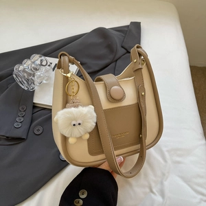 Sac hobo seau tendance en similicuir beige et marron avec un charme de monstre en peluche