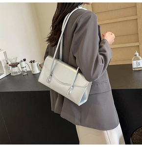 Silver rectangular underarm bag with metallic finish and long strap shown on model