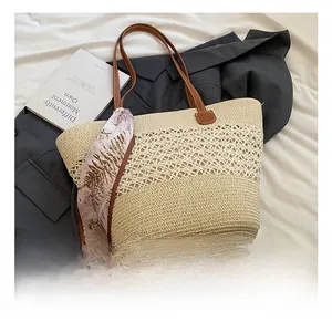 Detail of woven straw tote bag featuring leather straps and decorative floral silk scarf