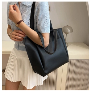Close-up of black leather tote bag with grainy texture and minimalist design on shoulder