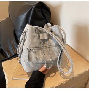 Detail of grey marble textured bucket bag with silver hardware on a stone surface