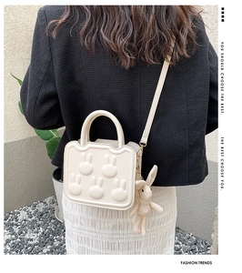 Detailed back view of a white crossbody bag with 3D bunny accents and plush charm