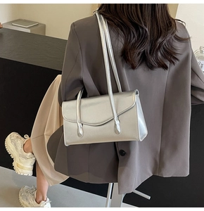 Street style shot of a trendy silver underarm bag with slim shoulder straps and metallic finish