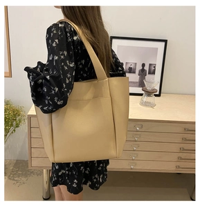 Detail of a large beige tote bag with litchi texture and shoulder strap for daily use