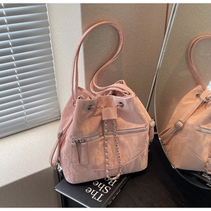 Detail of pink drawstring bucket bag with crinkled texture and silver chain strap