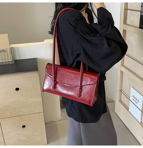 Detail of burgundy glossy faux leather underarm bag with smooth oil wax finish texture