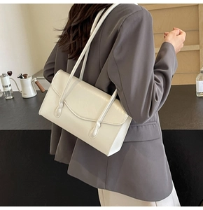 Close-up of a cream white minimalist shoulder bag with dual straps and glossy finish