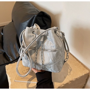 Detail of silver bucket bag showing drawstring closure and metallic pleated texture