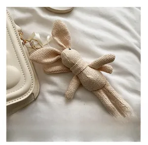 Detail of a white knitted rabbit charm attached to a cream quilted chain handbag