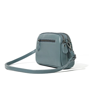 Blue leather crossbody bag with three zip pockets and pebbled texture, 45-degree view