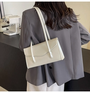 Close-up of minimalist cream white underarm shoulder bag worn on a grey blazer outfit