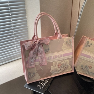 Pink floral embroidered tote bag with stylish ribbon and bow detail in a bright room