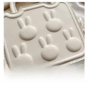 Detail shot of ivory leather handbag featuring embossed bunny pattern and neat stitching