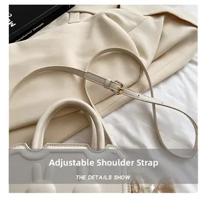 Detail of adjustable shoulder strap and gold hardware on cream white handbag