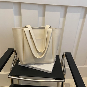 Minimalist beige tote bag in pebbled faux leather with front pocket for daily commute