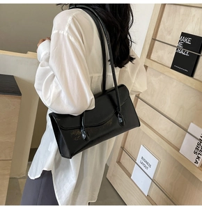 Minimalist black shiny rectangular PU leather shoulder bag carried by a model