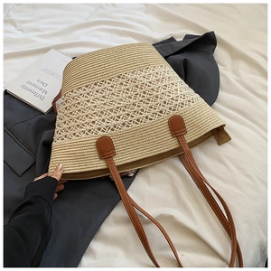 Détail du sac cabas en paille tissée avec anses en cuir marron et texture ajourée