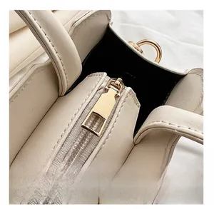 Close-up of smooth gold-tone zipper hardware on minimalist cream leather handbag