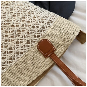 Détail du sac cabas en paille tissée bicolore avec bandoulière en cuir marron cousu