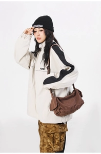 Brown canvas messenger bag styled with an oversized color-block streetwear jacket