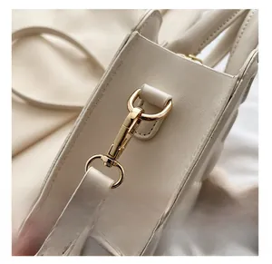Detailed macro view of premium light gold metal hardware on a cream leather handbag