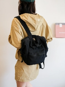 Rear view of model wearing a minimalist black canvas backpack with large capacity